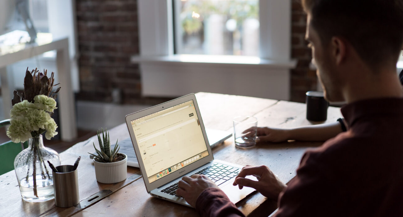 Pekerja profesional di depan laptop mengelola alur kerja komputasi dan supervisi agen kecerdasan buatan