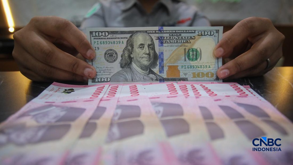Petugas menghitung pecahan mata uang dolar AS dan rupiah di 2026