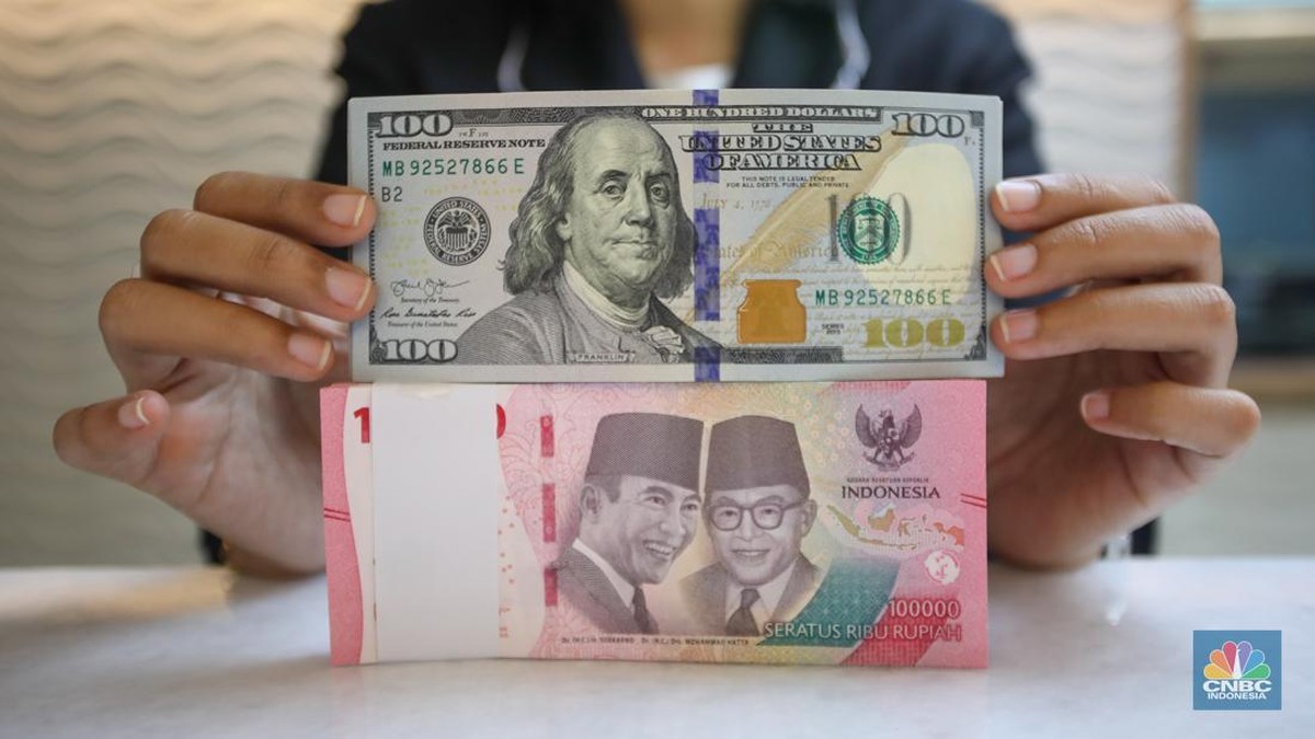 Petugas menunjukkan uang dolar as dan rupiah