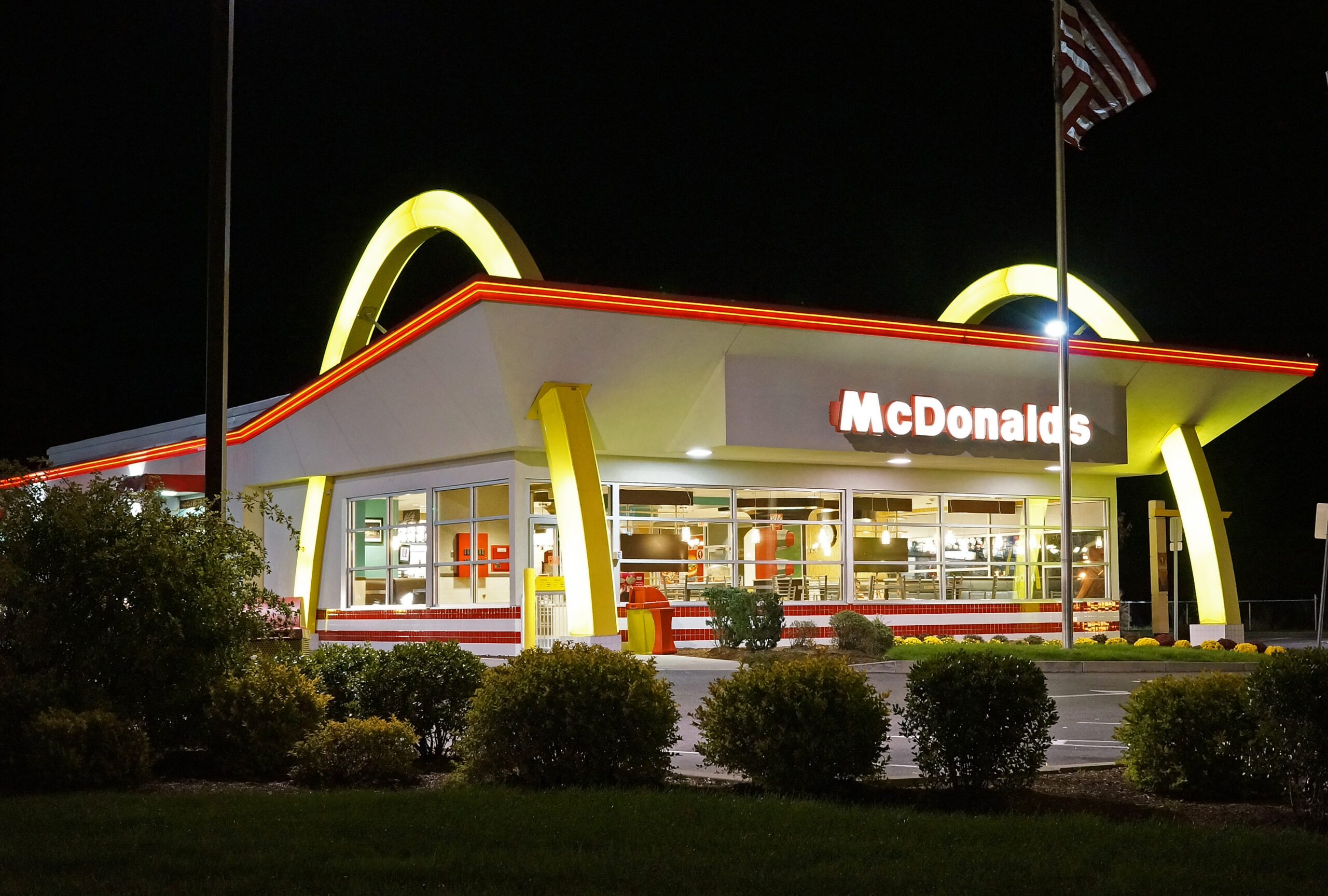 Papan logo Golden Arches restoran cepat saji McDonald's dengan latar langit cerah.
