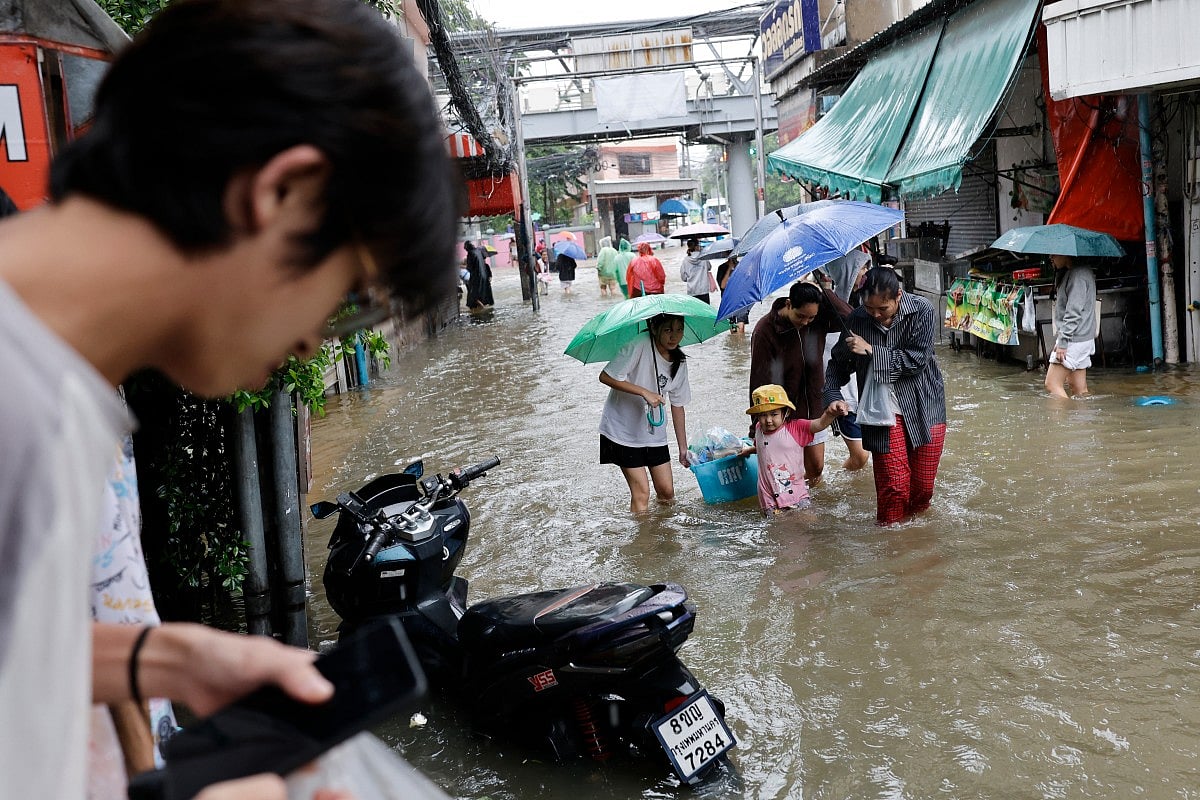 Warga Bangkok menerjang banjir di distrik Bang Bua pada 26 September 2026