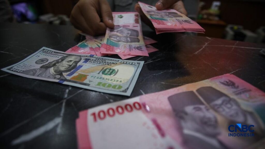 Petugas menunjukkan uang pecahan dolar Amerika Serikat dan rupiah di Dolar Asia Money Changer Jakarta