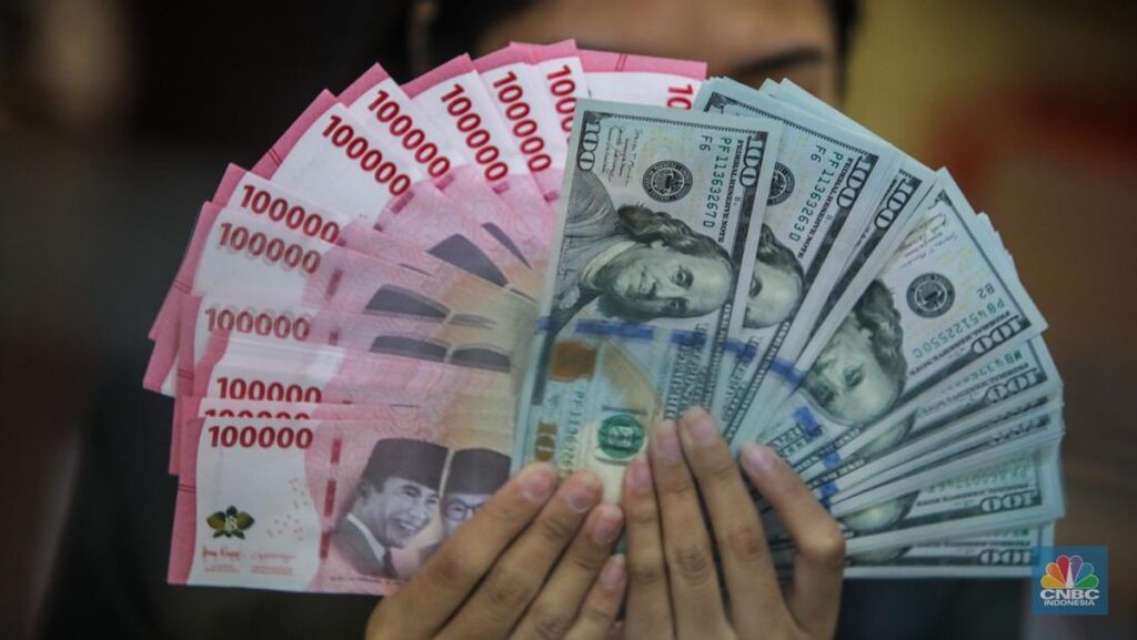 Petugas menghitung lembaran uang rupiah dan dolar AS di gerai penukaran valuta asing