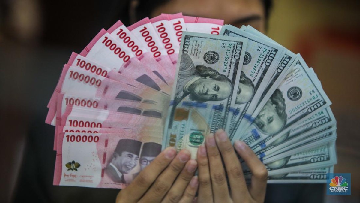 Petugas menghitung lembaran uang rupiah dan dolar AS di gerai penukaran valuta asing